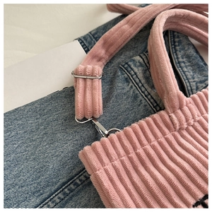 Close-up of pink corduroy tote bag featuring silver metal buckle and letter print