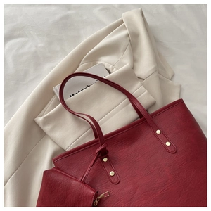 Detail of burgundy tote bag set with pebble leather texture and gold metal studs