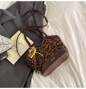 Detail of leopard print bucket bag with leather base, gold logo and bear charm
