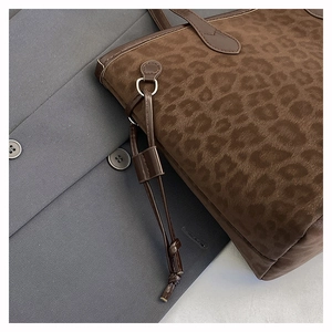 Close-up of vintage leopard print tote bag with premium leather handles on grey blazer