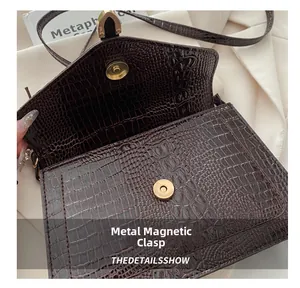 Detail showing crocodile texture and gold magnetic snap on dark brown crossbody bag
