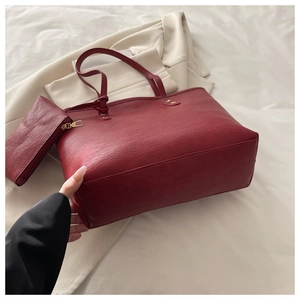 Detail of burgundy tote bag set with matching pouch and textured leather finish