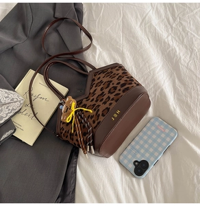 Detail of leopard print plush handbag with brown leather trim and cute bear charm