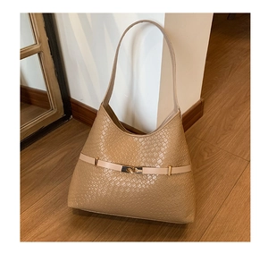 Detailed view of woven texture and golden metal clasp on light brown shoulder bag