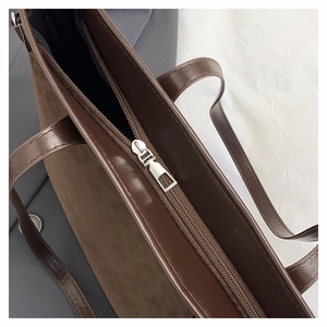 Detail eines glatten Metallreißverschlusses an einer dunkelbraunen Wildleder-Tote