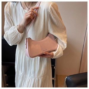 Detailed side view of a light pink crescent underarm bag worn on the shoulder