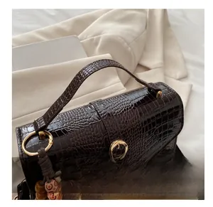 Detailed close-up of dark brown crocodile pattern handbag with gold hardware and bead detail