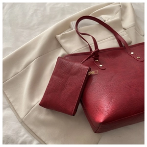 Close-up of bright red tote bag texture with gold rivets and matching zipper pouch