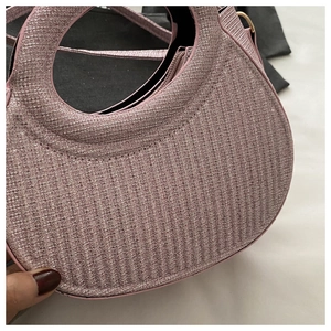 Detail of pink glitter crescent handbag with signature circular cutout handle design