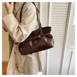 Detailed view of deep brown oily leather tote bag with gathered pleats and silver buckle
