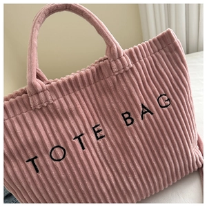Detail of pink corduroy fabric and black TOTE BAG embroidery on the casual handbag