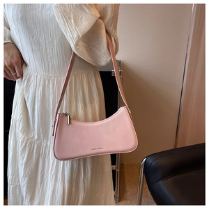 Close-up of a pale pink leather baguette bag with logo detail and adjustable shoulder strap