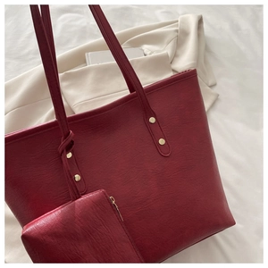 Detail of vintage burgundy tote bag set with matching pouch and golden hardware