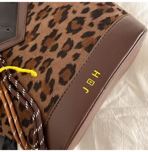 Detail of leopard print canvas and brown leather stitching with braided rope trim