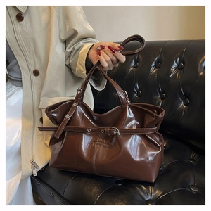 Detail of dark brown ruched tote bag in glossy PU leather with buckle strap decoration