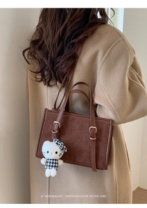 Dettaglio della borsa tote retrò in pelle marrone con patchwork e ciondolo Kitty