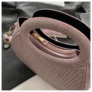 Detail of glittery pink fabric handbag with gold zipper and round handle design