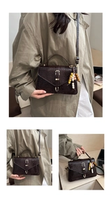 Detail of dark brown faux crocodile leather bag with gold buckle and beaded fringe charm