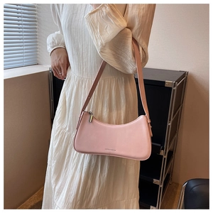 Pink faux leather crescent shoulder bag styled with a white pleated dress in a soft light