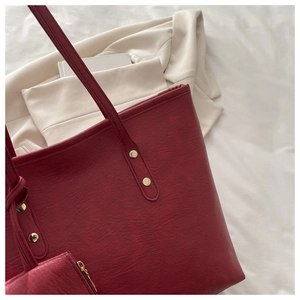 Detail view of burgundy tote bag with matching pouch and reinforced gold rivet handles