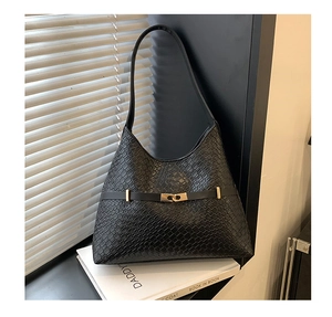 Detailed view of black woven texture leather bucket bag with gold clasp and shoulder strap