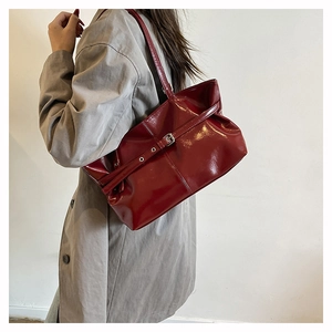 Dettaglio della borsa a spalla in pelle verniciata rosso scuro con fibbie argento