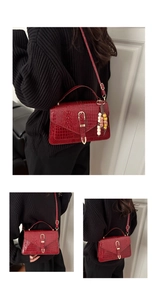 Detail view of red crocodile pattern shoulder bag with golden clasp and beaded charm