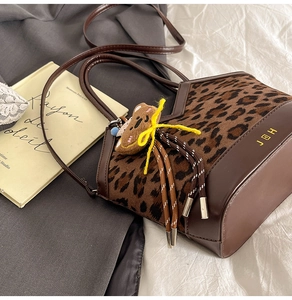 Detail of leopard print bucket bag with deep brown leather trim and a cute bear charm