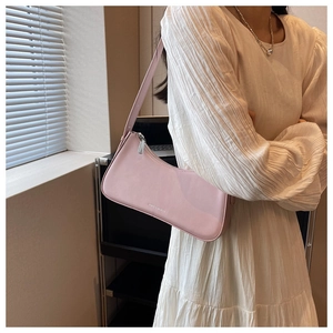 Detail view of pink leather underarm bag with zipper closure and fine shoulder strap