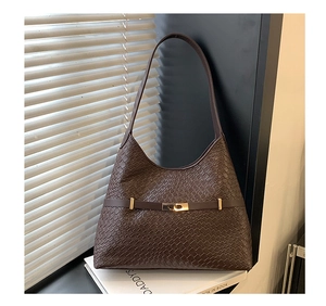 Detail of dark brown tote bag with embossed leather texture and gold metal buckle