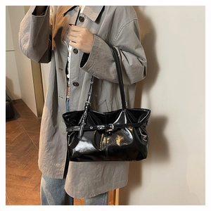 Detailed view of black patent leather tote bag with retro belt buckle decoration