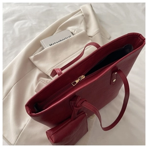 Detail view of burgundy leather tote bag featuring a matching mini pouch and gold zipper