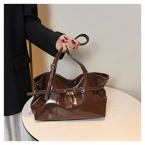 Close-up of brown glossy patent leather tote with metal buckle and cylindrical handle