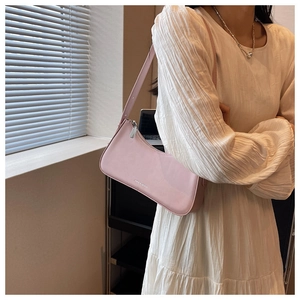 Pink leather shoulder bag worn by a model with adjustable strap and silver zipper detail