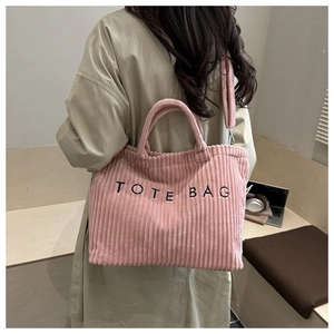 Pink corduroy tote bag with TOTE BAG lettering shown in a stylish lifestyle setting