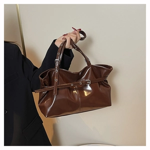 Close-up of deep brown patent leather tote bag with glossy finish and metal buckles