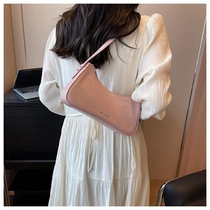 Pink crescent underarm bag shown on model wearing a white dress in a minimalist setting