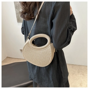Detailed texture of beige woven handbag with circular hollow handle and crossbody strap