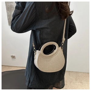 Detail of beige woven crossbody bag featuring a unique circular handle and metal hardware