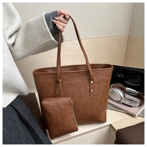 Detail of dark brown tote bag set with matching coin purse and stylish rivet handle design