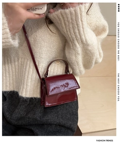 Detail of burgundy patent leather mini bag with elegant top handle and thin shoulder strap