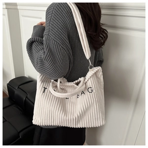 Detail of white corduroy tote bag with TOTE BAG embroidery and adjustable shoulder strap