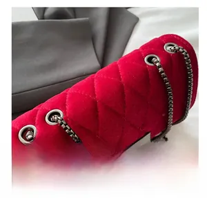 Detail of red velvet quilted handbag showing metal eyelets and metallic chain strap