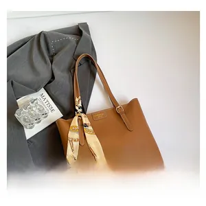 Caramel brown leather tote bag with elegant floral scarf detail and gold logo plate