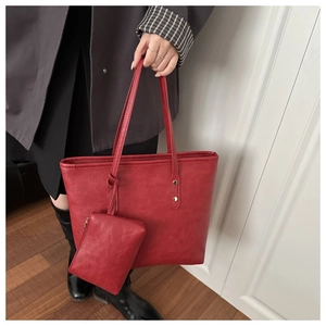 Detail of red leather tote bag with matching zippered pouch and gold rivet accents