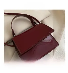 Macro shot of minimalist wine red patent leather handbag with glossy flap and buckle detail