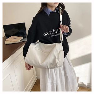 Detail view of a white large capacity nylon crossbody bag with functional zip pockets