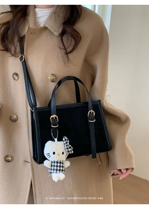 Dettaglio della borsa tote nera in pelle con un simpatico ciondolo a forma di gattino