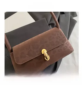Detail view of brown suede baguette bag featuring a sleek golden metal clasp