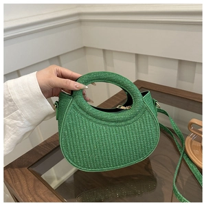 Detail of green shimmering woven handbag with circular handle and thin crossbody strap